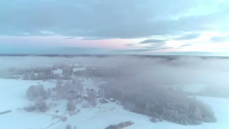 toma aérea de drones volando sobre el pintoresco campo cubierto de nieve fresca en polvo a través de nubes blancas durante la noche