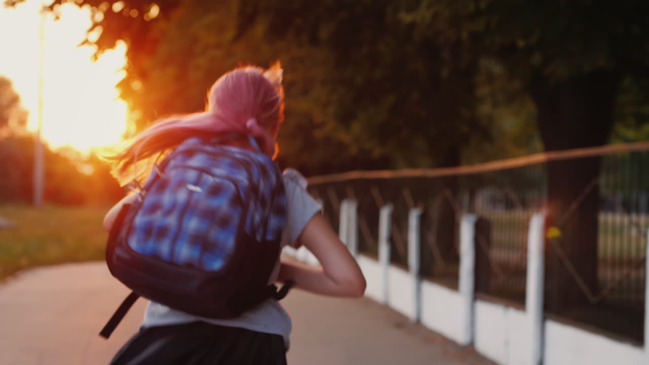 A Girl With A Schoolbag Behind Her Runs Along The Alley To The School In The Sun Back To School