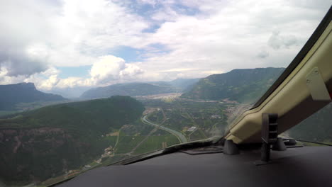 view from the cockpit of a corporate jet circling for landing in a small valley in the italian alps