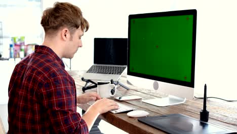 joven hombre caucásico freelance escribiendo en el teclado y mirando la pantalla simulada