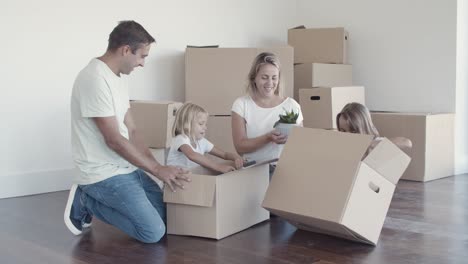 happy family couple and kids unpacking things