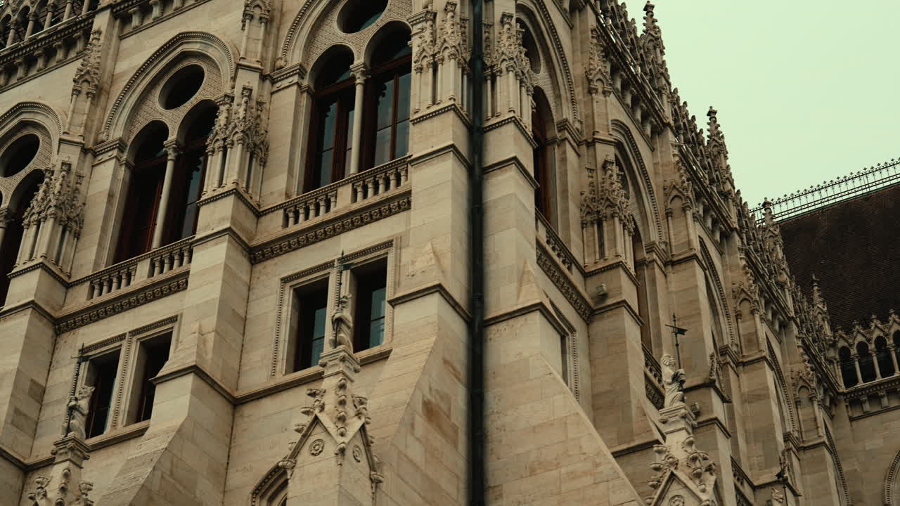 Close-up view of the Hungarian Parliament Building in Budapest, Hungary, showing ornate Neo-Gothic details and historic stone design. Cinematic slide shot showing facade, windows and its art
