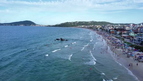 toma estática aérea de turistas bañándose en el mar en la playa bombas, brasil