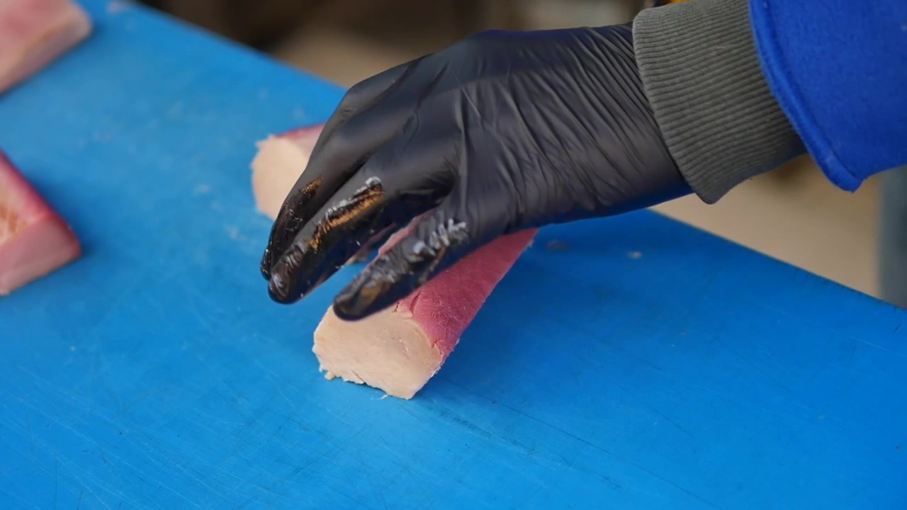 Chef che affetta filetto di tonno fresco su tagliere blu