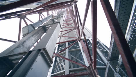 pipes and supports at the grain-drying complex. high steel constructions at the backdrop of sky. view on the structure from below.