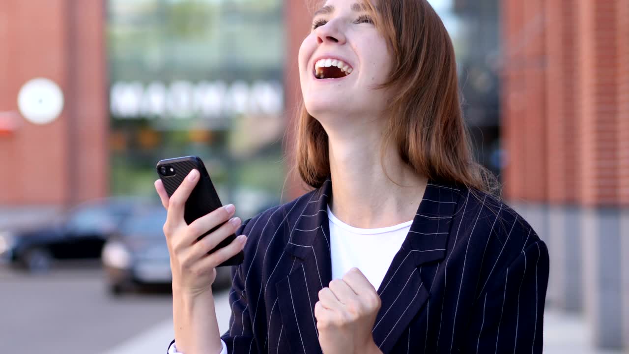 스마트폰을 사용하면서 성공을 축하하는 사업가