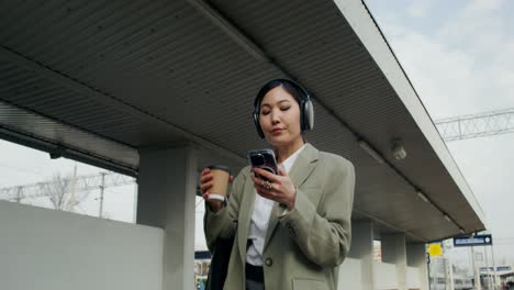 mujer en la estación de tren con café y teléfono