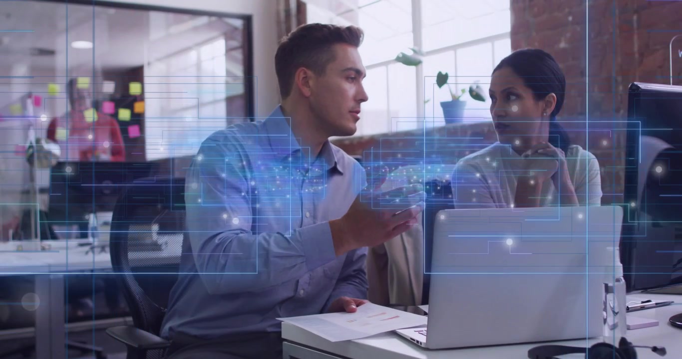 Tech team picking chart and pointing at laptop while pulsing holographic overlay clarifying data
