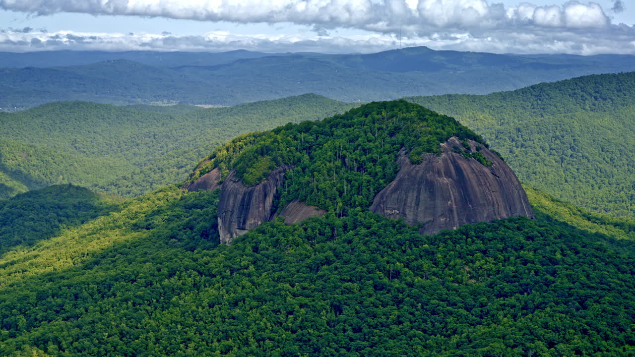 Drone footage capturing a towering mountain standing alone, set apart from the nearby peaks
