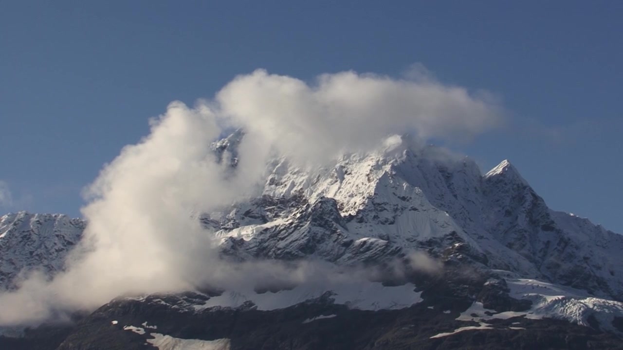 Hvit, fluffy sky på toppen av et snødekt fjell i Glacier Bay, Alaska, på en solrik dag