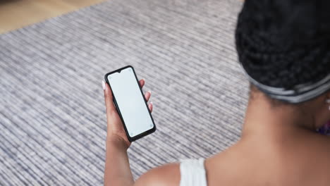 Young-African-American-woman-holds-a-smartphone-at-home,-with-copy-space