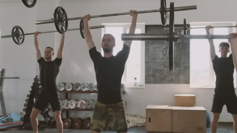 a group of sportswomen and sportsmen lift weights during a class