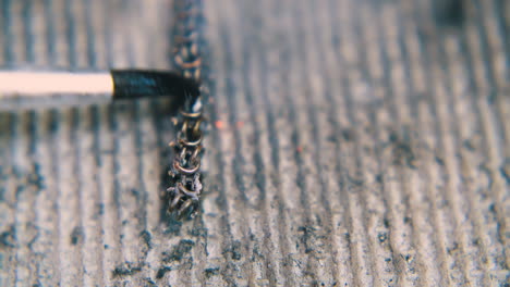 person-uses-brush-to-descale-heated-chain-extreme-closeup