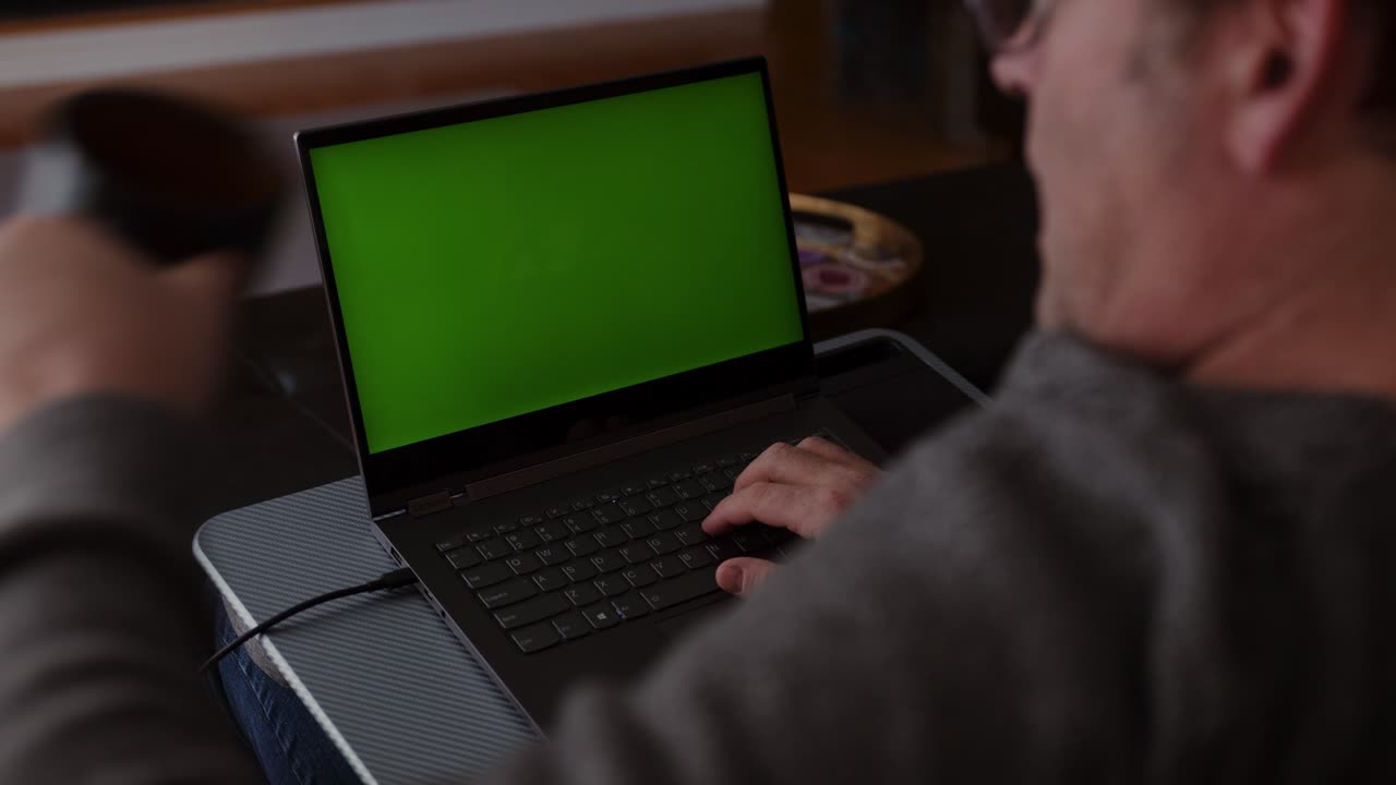 Computer Green Screen While an Older Man Works and Drinks Coffee