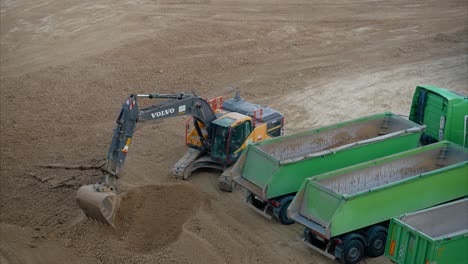 volvo excavator loading dump trucks on construction site