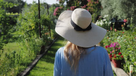 woman in hat walking through garden - steadicam shot