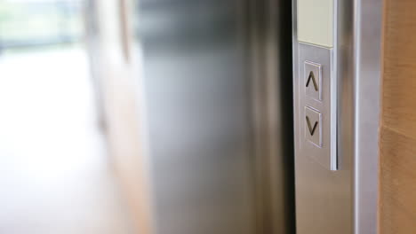 pressing elevator button, person holding documents, waiting for elevator to arrive