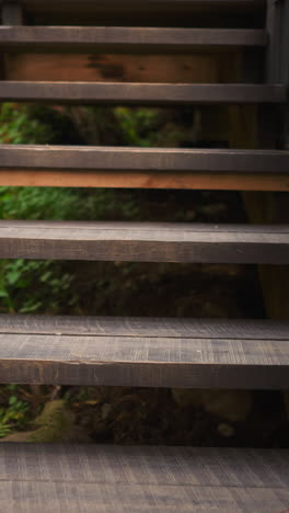 escalera de madera de la casa de campo. elemento para el ascenso y descenso en el edificio del complejo de glamping para turistas rodeado de denso bosque con plantas