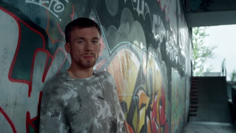 Stylish-man-turning-head-to-camera-at-skatepark.-Guy-hipster-smiling-to-camera.