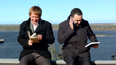 young man on phone disturbs man withbook