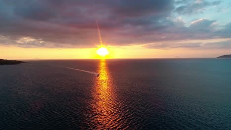 toma aérea de una lancha rápida de lujo que llega al océano al atardecer