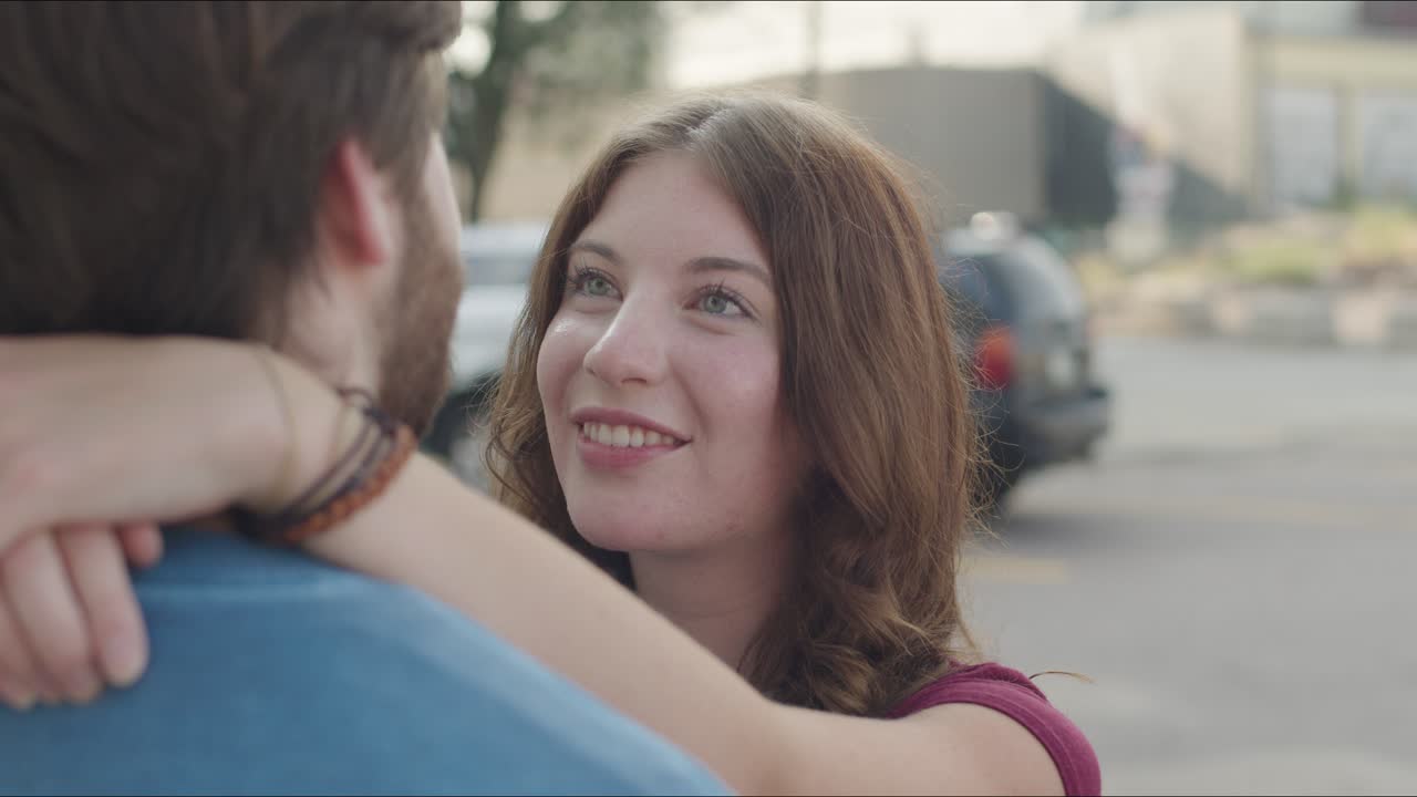 Close up of woman's face with her arm around man talking to each other.