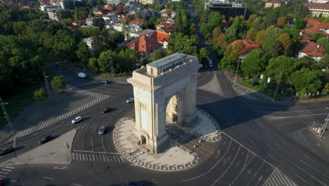 Vista-De-Arriba-Hacia-Abajo-Sobre-El-Arco-Del-Triunfo-En-Bucarest,-Rumania,-Con-Automóviles-Circulando-En-La-Rotonda.