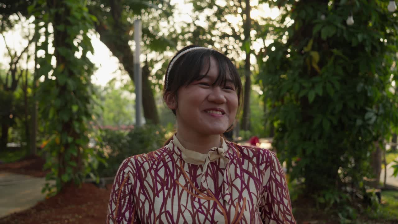 Delighted young Asian female, local park location, slow motion scenery