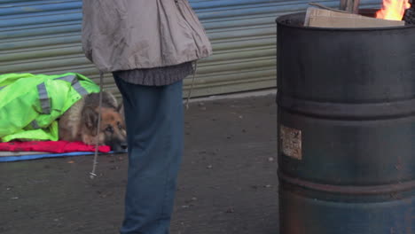 A-cold-homeless-woman-warms-her-hands-by-a-fire-trying