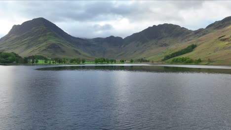 Vista-Aérea-De-Bajo-Nivel-Del-Lago-Buttermere-Hacia-La-Flota-Con-Lucio-Y-Montones-De-Heno,-El-Distrito-De-Los-Lagos,-Inglaterra