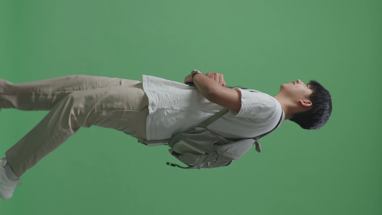 웃는 아시아 남성 학생이 태블릿을 들고 녹색 스크린 스튜디오에서 는 측면 시각