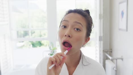 happy asian woman brushing teeth in bathroom, in slow motion