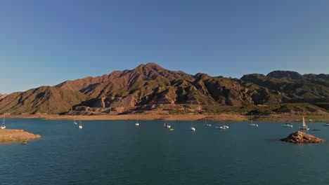 Low-aerial-dolly-shot-toward-a-group-of-anchored-sailboats-in-Mendoza,-Argentina