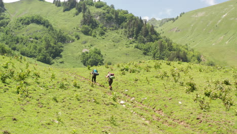 Two-hikers-walking-uphill-through-a-beautiful-Swiss-landscape