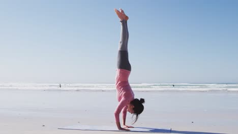 mujer caucásica haciendo posición de yoga en la playa y fondo de cielo azul