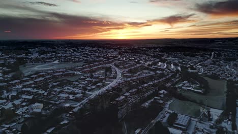 Luftaufnahme-Der-Morgendämmerung-Im-Winter-In-Yorkshire,-Die-Ländliche-Wohnhäuser-Und-Frostbedeckte-Dächer-Zeigt,-Während-Die-Morgensonne-Durch-Die-Wolken-Bricht