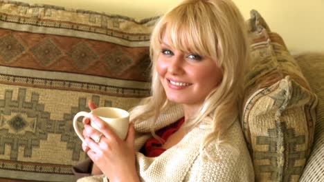 portrait of a blond woman drinking coffee sitting on sofa