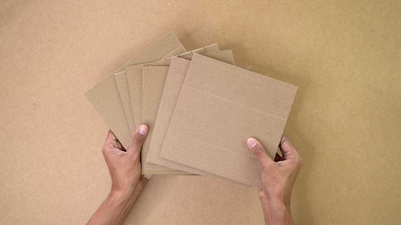 Hands holding multiple cardboard sheets prepared for DIY craft