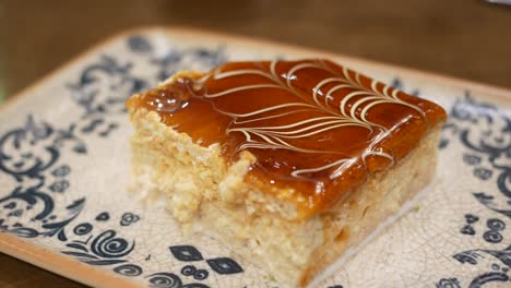 a slice of cake with caramel and white chocolate on a patterned plate