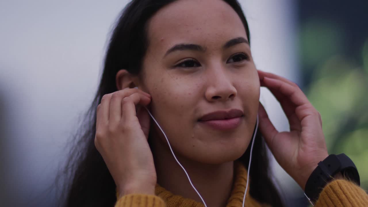 mujer asiática con auriculares escuchando música y sonriendo