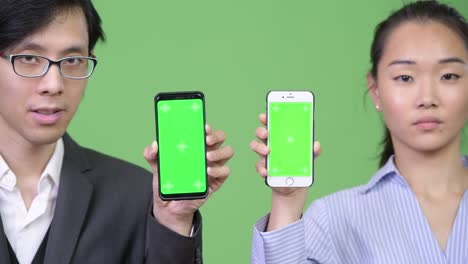 young asian business couple showing phone together