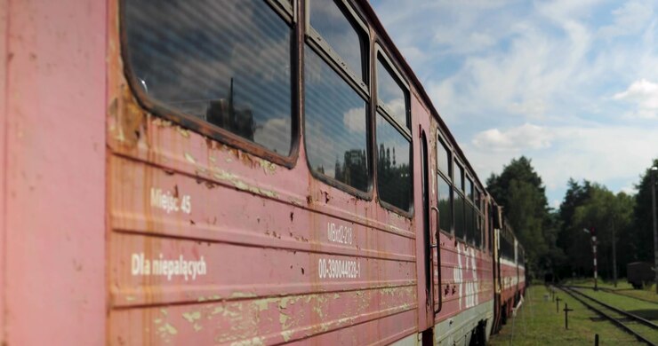 Old and rusting train carriages standing at an abandoned railway station on a sunny summer day, captured in a dynamic 4K shot