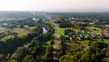 aerial view of rural road and homes leading into pavilosta town in western latvia.