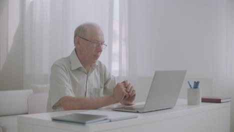 aged male lawyer is consulting client by internet using laptop with web camera sitting alone in his office