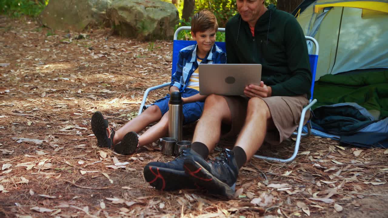 padre e hijo usando computadora portátil fuera de la tienda