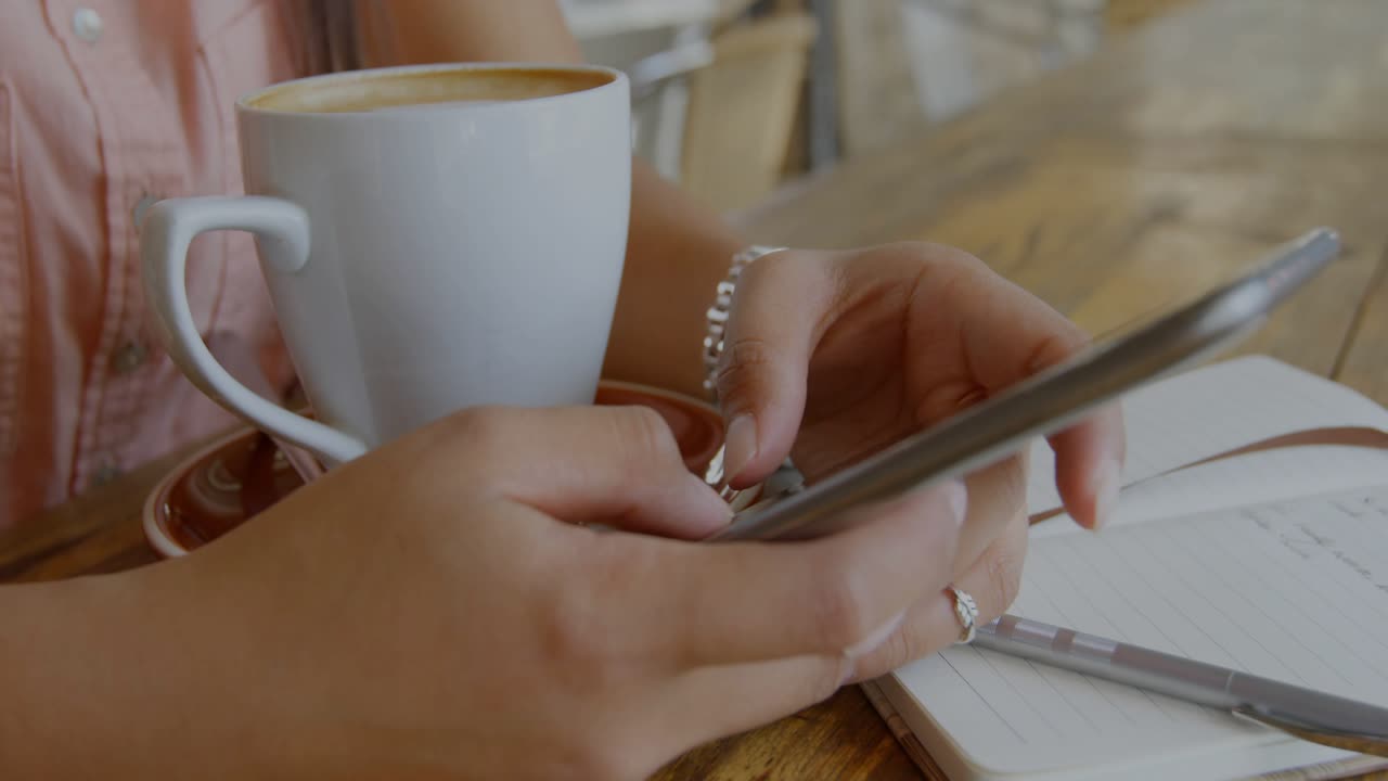 Donna che utilizza uno smartphone in una caffetteria, con sovrapposizione di barre, globo e codice durante la revisione dei dati per la tecnologia