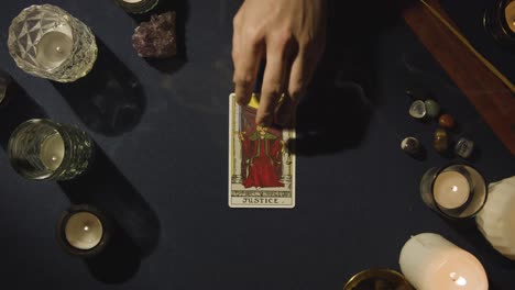 disparo desde arriba de una persona que da lectura de cartas de tarot colocando la tarjeta de justicia en la mesa
