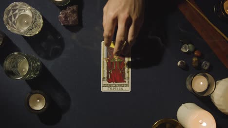 overhead shot of person giving tarot card reading laying down the justice card on table