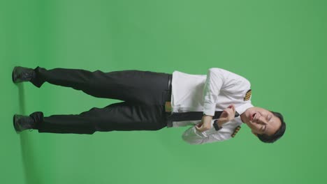 full body of asian man pilot dancing and celebrating while standing in the green screen background studio