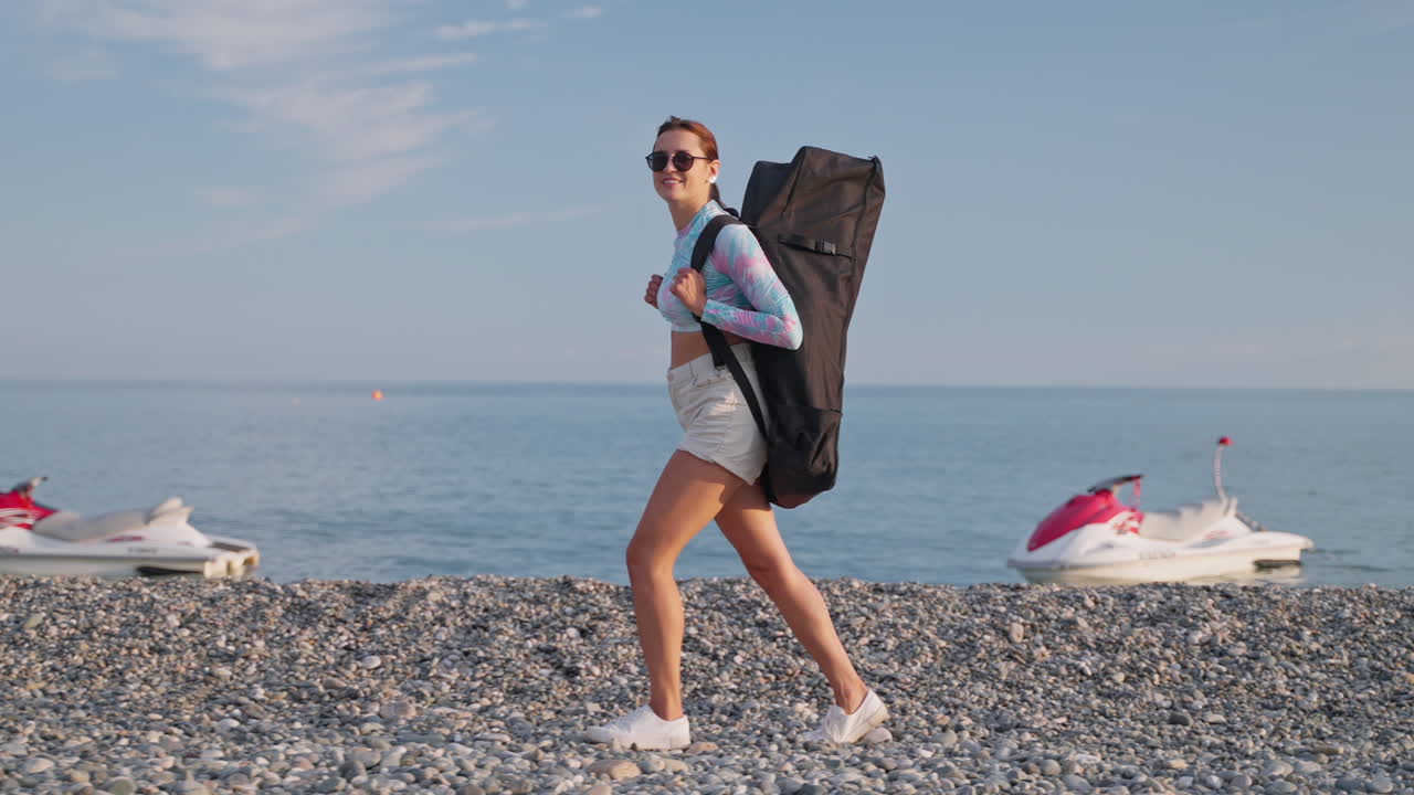 женщина с рюкзаком на пляже возле океана с реактивными лыжами